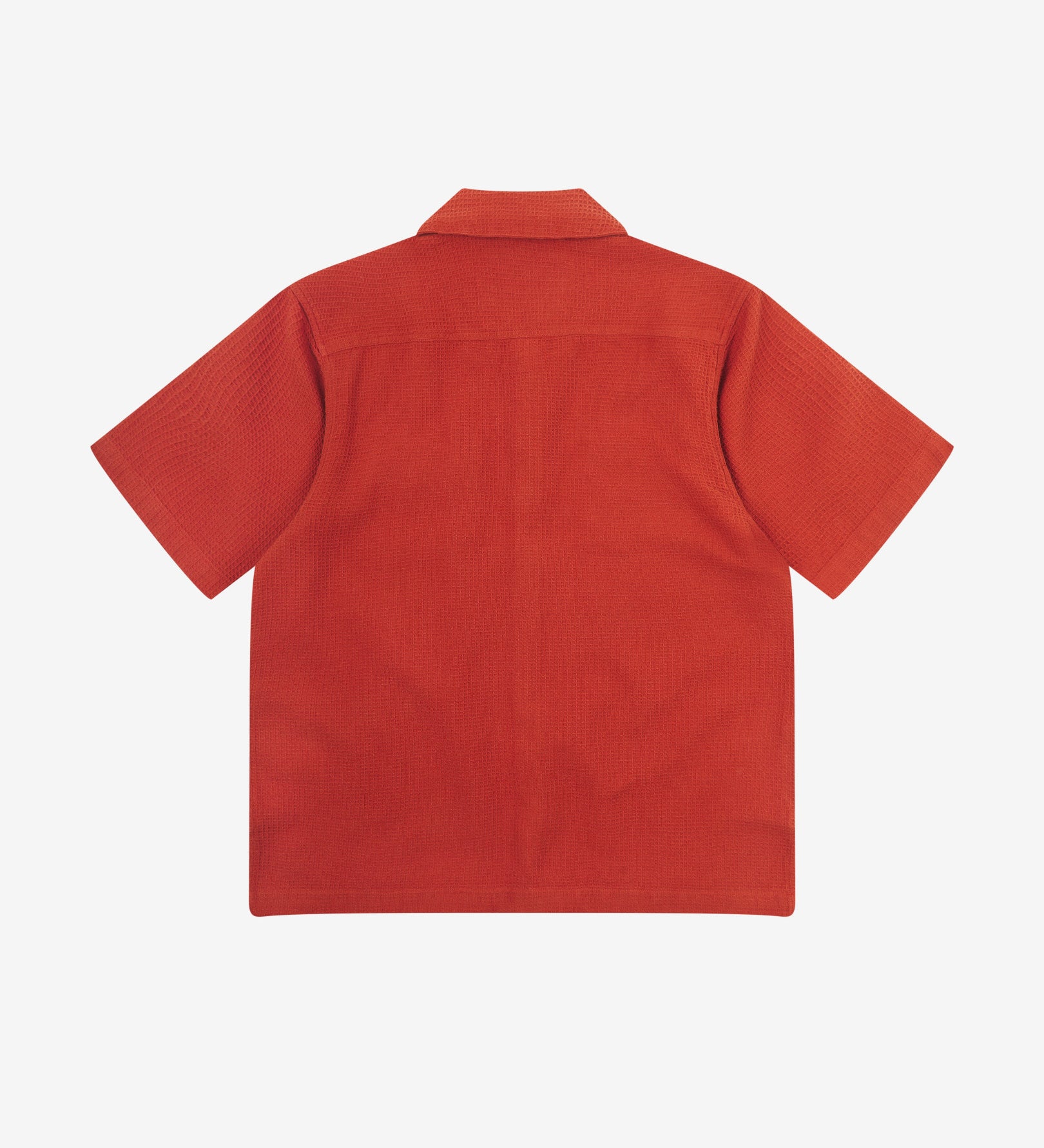 Reverse flat view of rust-red organic cotton waffle fabric short sleeve shirt from Uskees showing vent in hem and loose, relaxed silhouette.