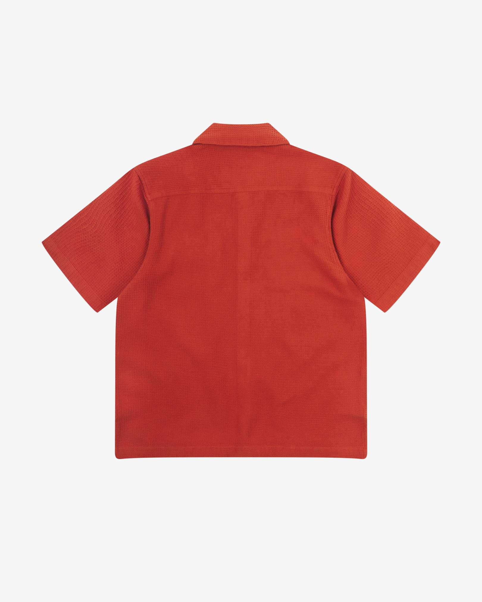 Reverse flat view of rust-red organic cotton waffle fabric short sleeve shirt from Uskees showing vent in hem and loose, relaxed silhouette.