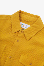 Close-up and angled front view of the 6007 Tasker shirt in yellow, showing the waffle texture, collar, hanging loop and matching corozo buttons.