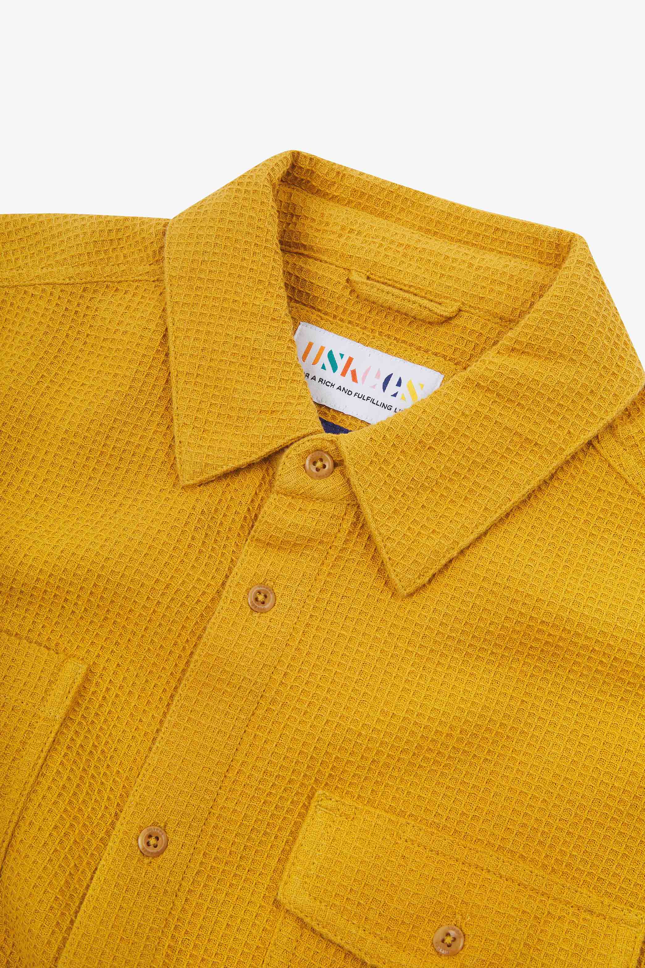 Close-up and angled front view of the 6007 Tasker shirt in yellow, showing the waffle texture, collar, hanging loop and matching corozo buttons.