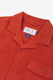 Close-up view of the #6008 shirt collar, showing weave of rust-red organic cotton waffle fabric, camp notched collar and Uskees branding label.