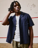 Top-half front view of model wearing an Uskees dark blue Cuban shirt demonstrating relaxed, casual fit and paired with grey marl t-shirt.