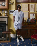 Full-length view of model wearing an Uskees blue, gold and white striped shirt and matching shorts.
