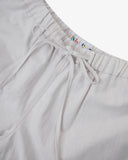 Close-up shot of Uskees off-white shorts with focus on the brand label and drawstring waist.