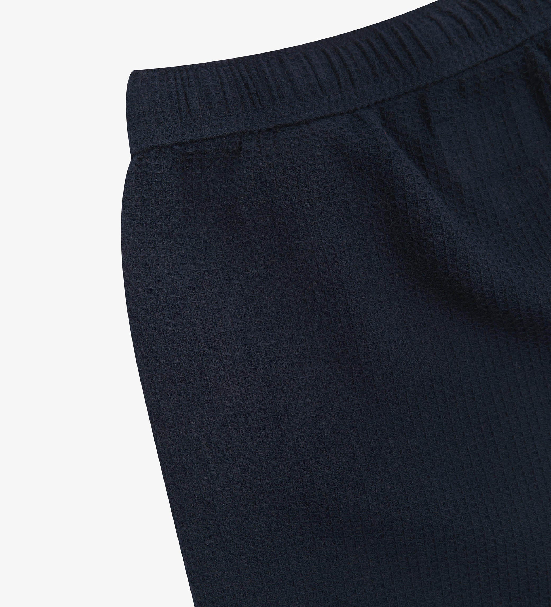 Close-up angled rear view of the #6009 Uskees shorts, presenting a closer view of the elasticated waistband and deep-blue waffle fabric.