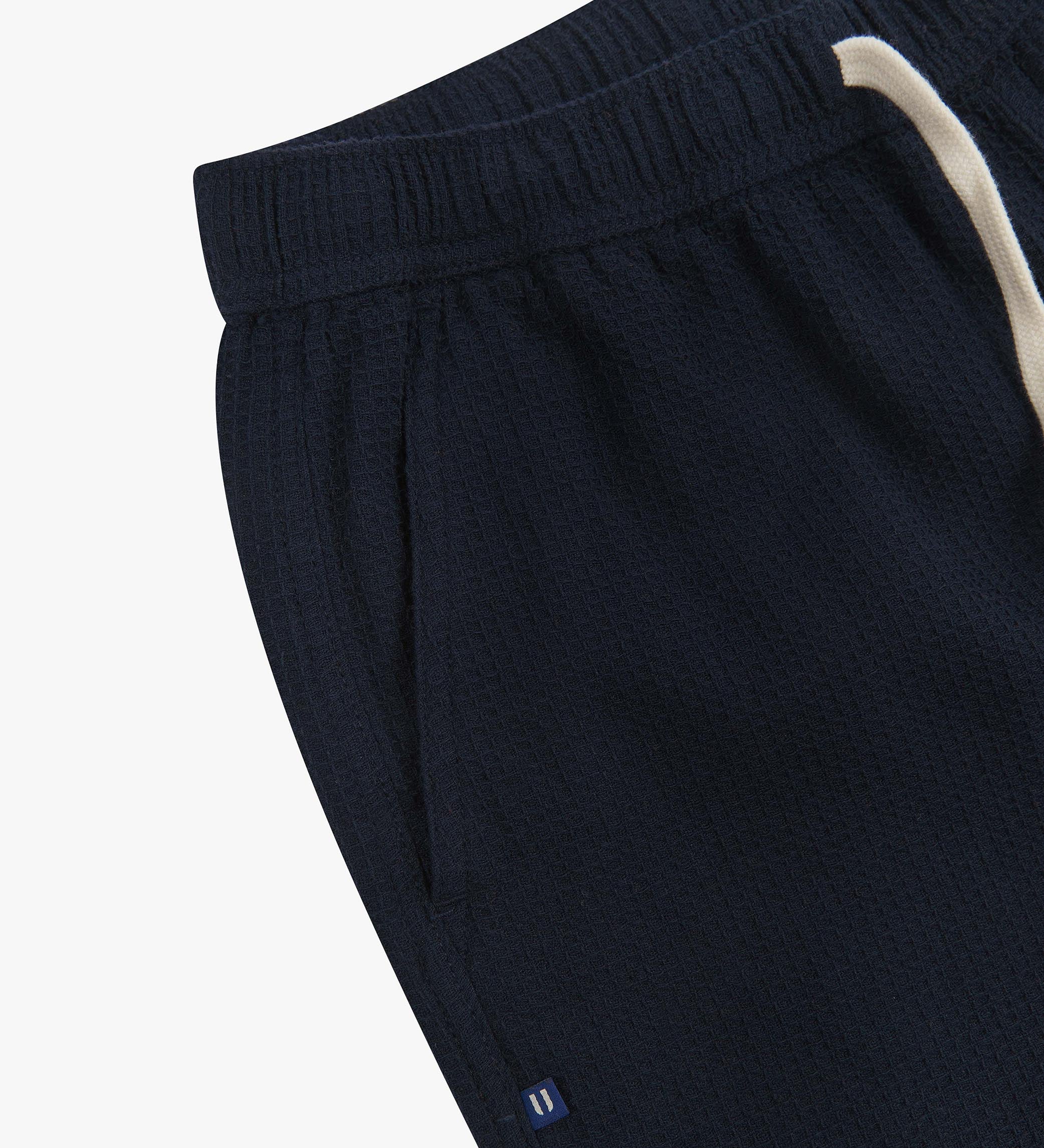 Close-up angled view of a side pocket, elasticated waist and drawstring of the casual deep-blue waffle cotton shorts.