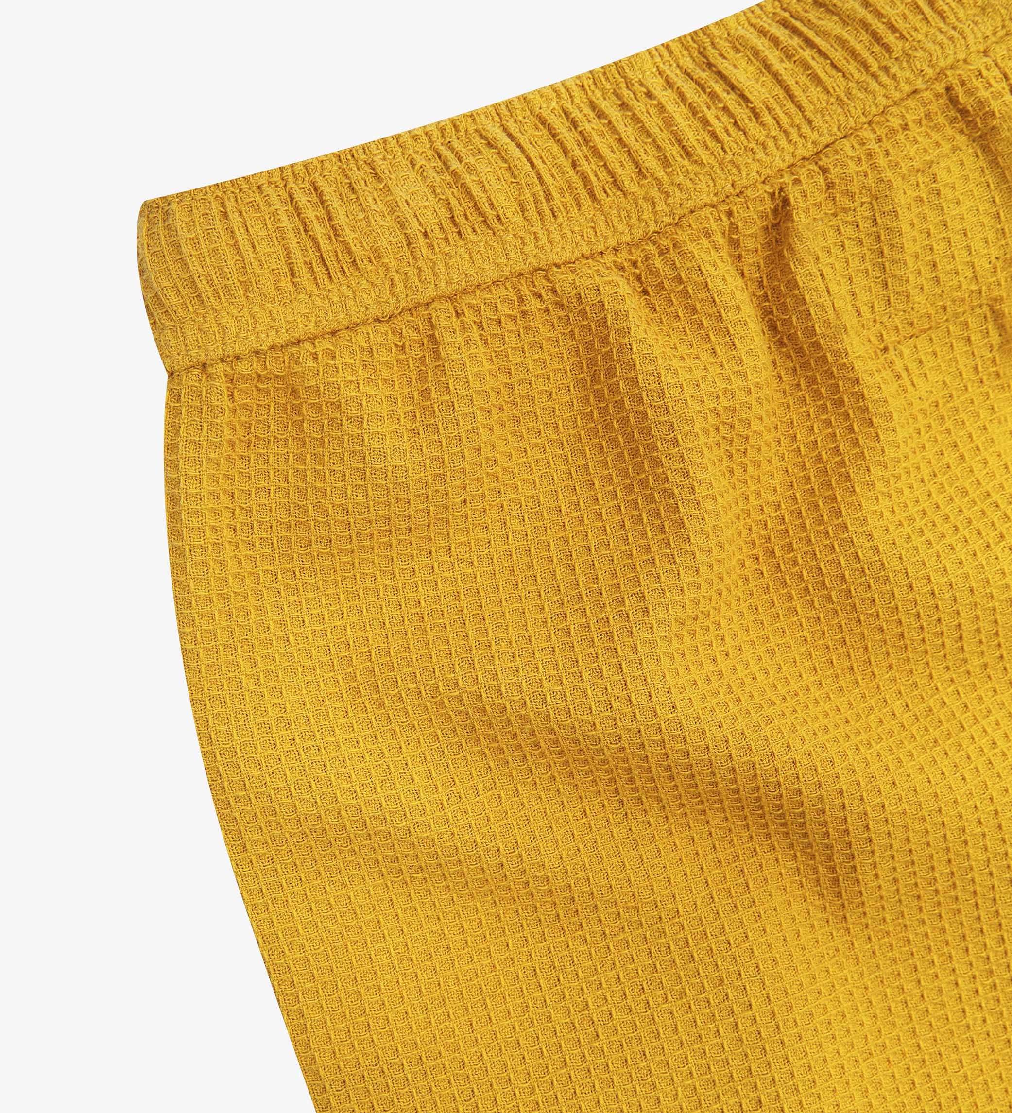 Close-up angled rear view of the #6009 Uskees shorts, presenting a closer view of the elasticated waistband and yellow waffle fabric.