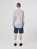 Back view of model wearing a Uskees blue pebble plaid lumberjack shirt showing the oversized fitting and the unbalanced hem.