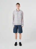 Male model wearing an Uskees blue pebble plaid lumberjack shirt and navy shorts.