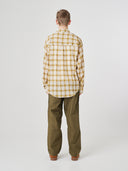 Back view of model wearing a Uskees sand pebble plaid lumberjack shirt showing the oversized fitting and the unbalanced hem.
