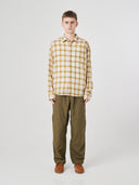 Male model wearing an Uskees sand pebble plaid lumberjack shirt and green uskees pants.