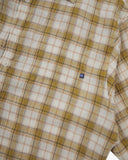Close-up of an Uskees sand pebble plaid lumberjack shirt with small sand brand logo tab on the pocket. 