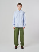 Man wearing Uskees light blue and white striped men's Oxford shirt, paired with Uskees green pants.