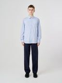 Full-length front view of man wearing Uskees blue, gold and white striped men's Oxford shirt.