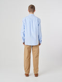Reverse view wearing Uskees light blue men's Oxford shirt, paired with Uskees khaki pants.