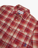 Close up of an Uskees red clay check long sleeved flannel shirt for men showing the chest pockets and collar detail.