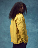 Side view of man wearing the Uskees wax storm jacket in British yellow.