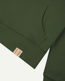 Front close view of Uskees coriander-green hoodie with clear view of brand logo on hem and kangaroo front pocket.
