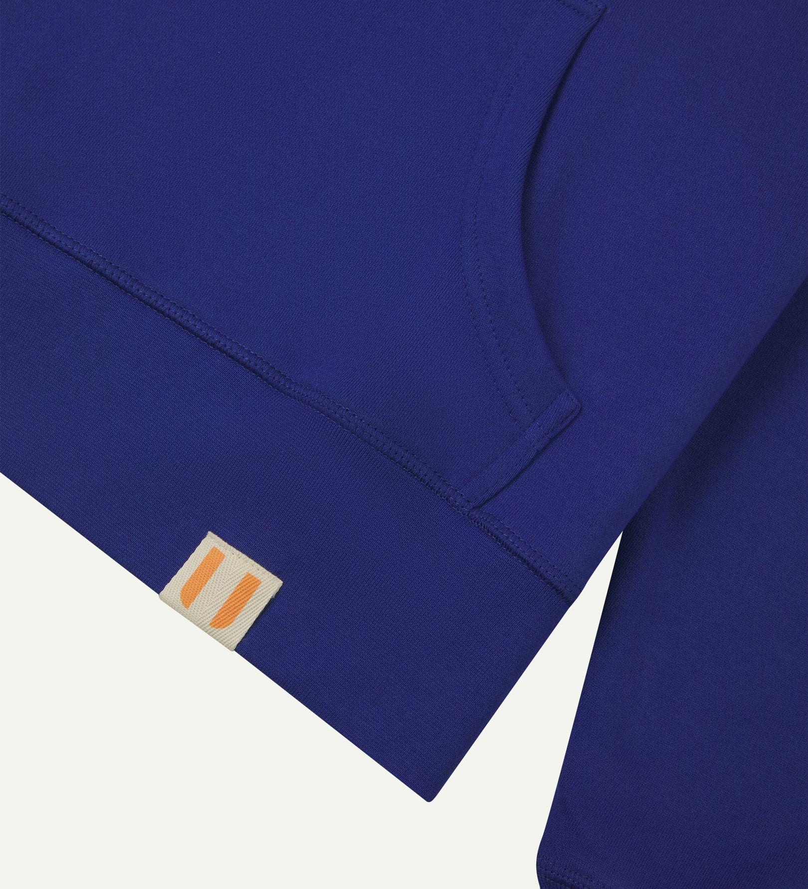 Front close view of Uskees 'ultra blue' hoodie for men with clear view of brand logo on hem and kangaroo front pocket.
