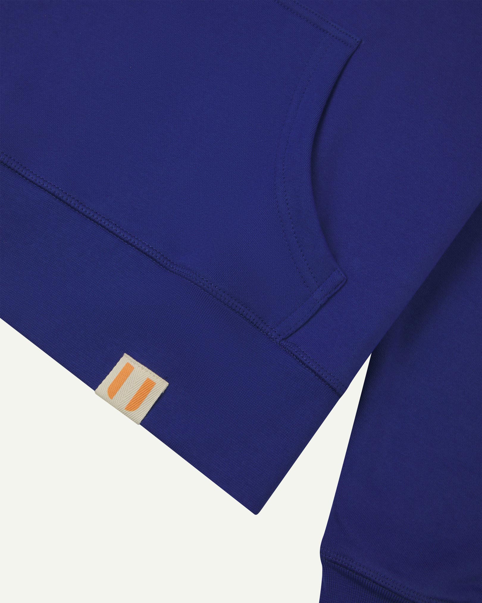 Front close view of Uskees 'ultra blue' hoodie for men with clear view of brand logo on hem and kangaroo front pocket.