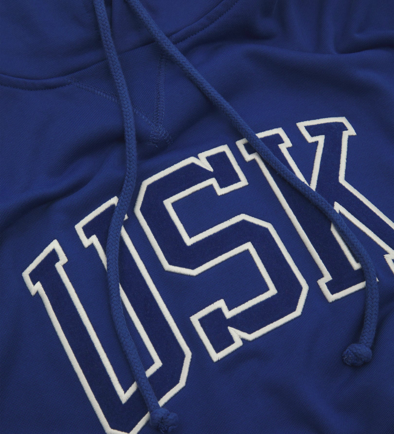 Front close shot of Uskees signature ultra blue men's hooded sweatshirt showing the 'USK' logo and hood drawstrings.