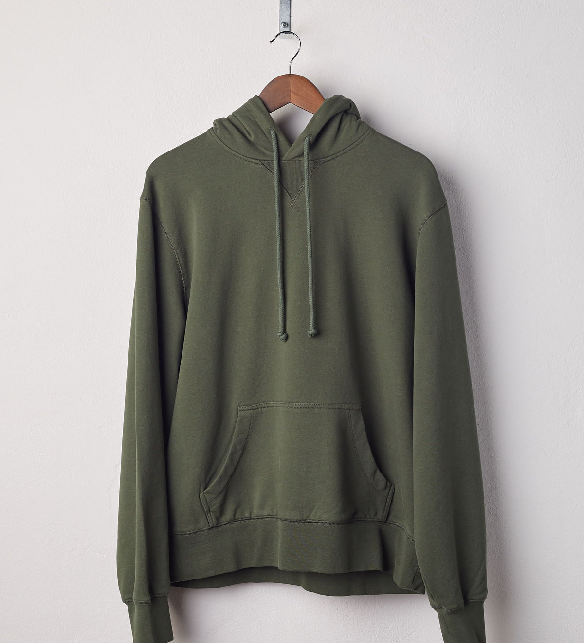 Front view of vine green organic heavyweight cotton #7004 jersey hooded sweater by Uskees presented on hanger.