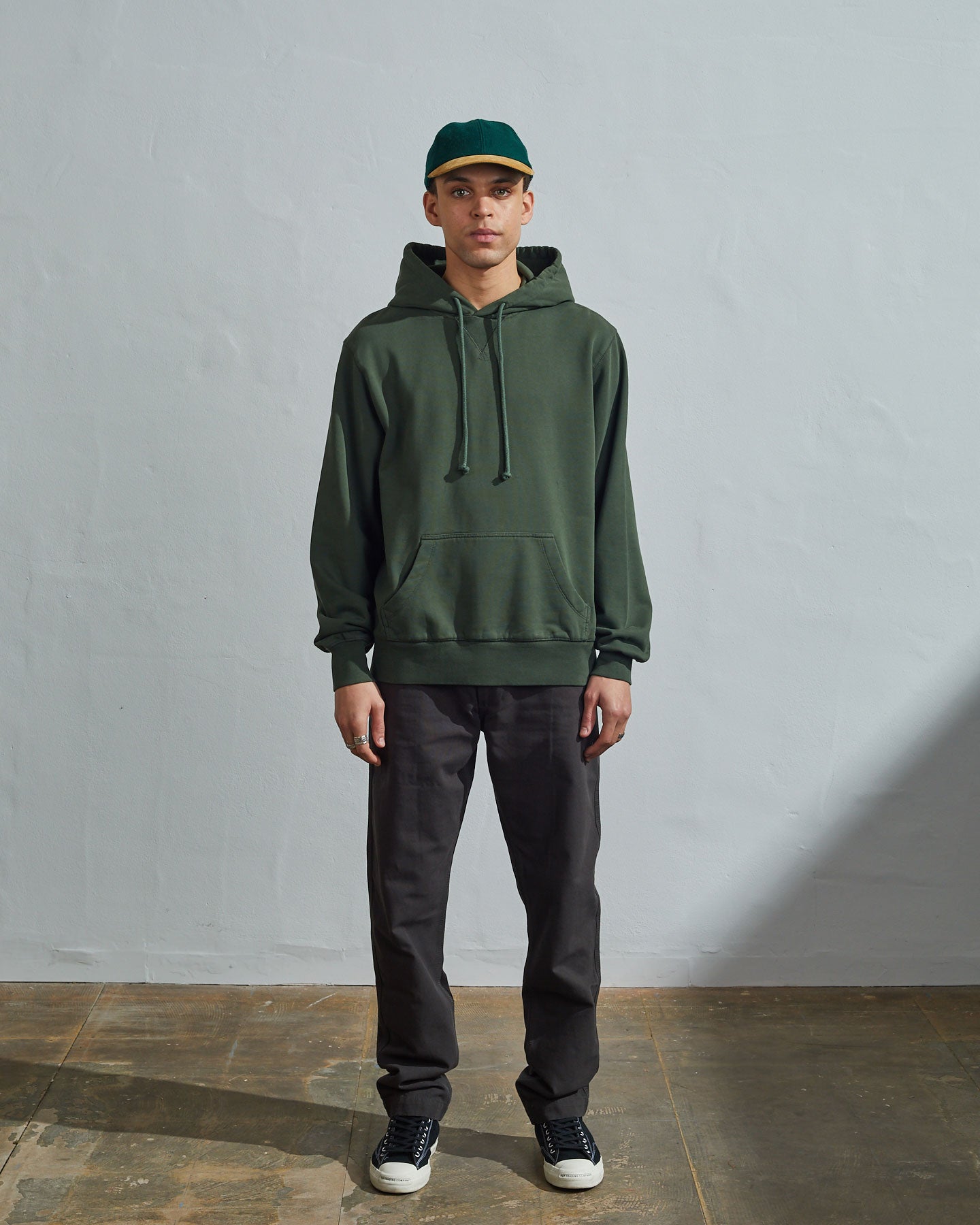 Full-length front view of model wearing vine green organic cotton #7004 jersey hooded sweater with front pouch pocket.