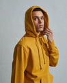 Side view of model wearing #7004 hoodie sweater with hood up and view of view of ribbed cuffs.