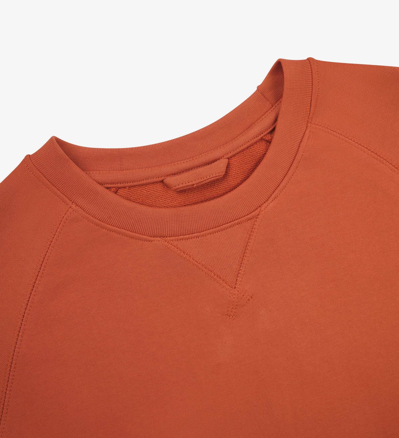 Close-up view of crew neck collar with decorative v-insert on Uskees cinnamon-orange heavyweight cotton jersey sweatshirt.