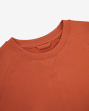 Close-up view of crew neck collar with decorative v-insert on Uskees cinnamon-orange heavyweight cotton jersey sweatshirt.