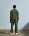 Full-length back view of model wearing coriander-green, relaxed cut organic cotton #7005 jersey sweatshirt with ribbed cuffs and hem.