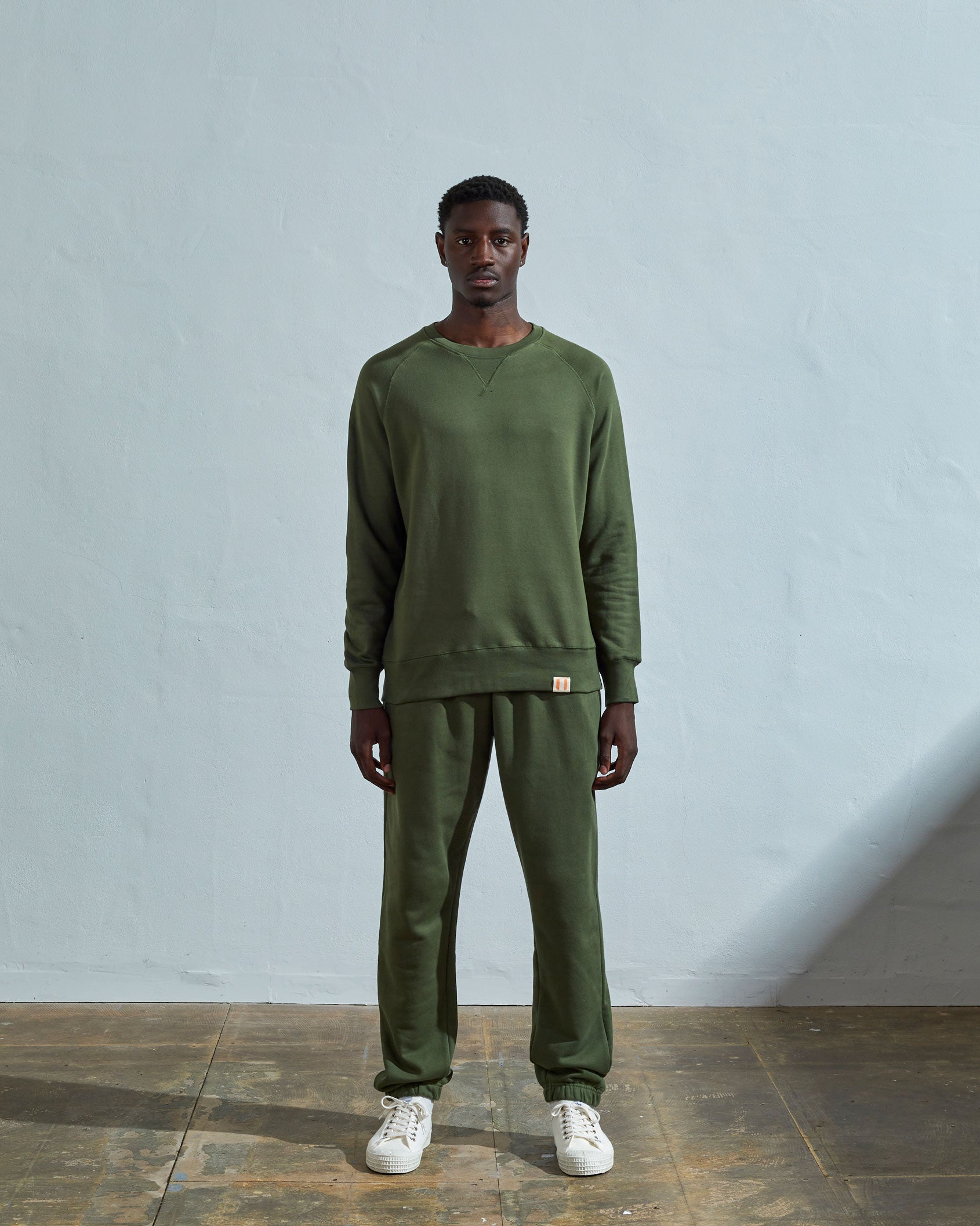 Full-length front view of model wearing coriander-green organic cotton #7005 jersey sweatshirt with raglan sleeves. Paired with matching Uskees pants.