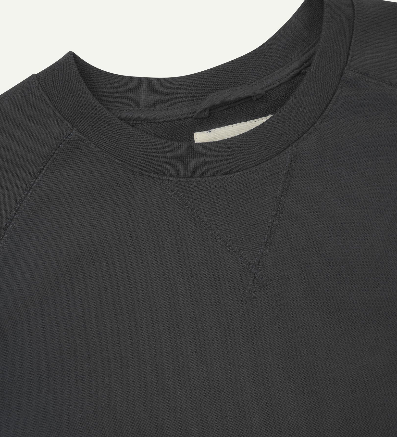 Close-up view of crew neck collar with decorative v-insert on Uskees faded black heavyweight cotton jersey sweatshirt.