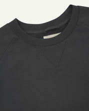 Close-up view of crew neck collar with decorative v-insert on Uskees faded black heavyweight cotton jersey sweatshirt.