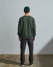 Full-length back view of model wearing vine green, relaxed cut organic cotton #7005 jersey sweatshirt with ribbed cuffs and hem.