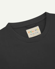 Close view of uskees #7006 men's short sleeve Tee in faded black showing the brand/size label at neck.