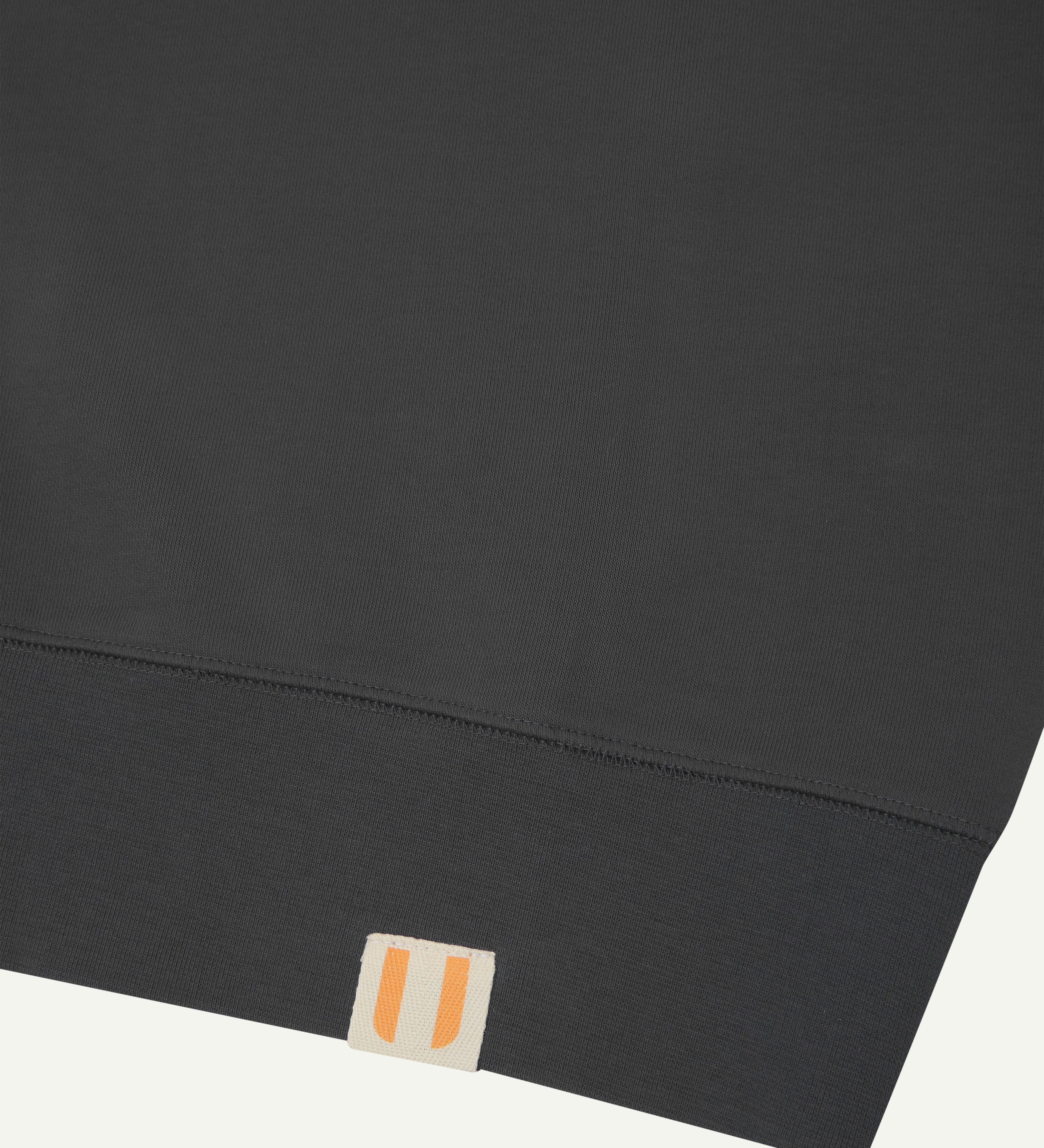 Close-up view of hem showing uskees logo label - dark grey organic heavyweight cotton #7005 sweatshirt for men.