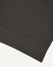 Close up shot of hem on Uskees 7005 crew neck sweatshirt in faded black