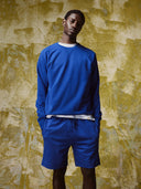 Male model wearing an Uskees ultra blue sweatshirt and matching shorts.