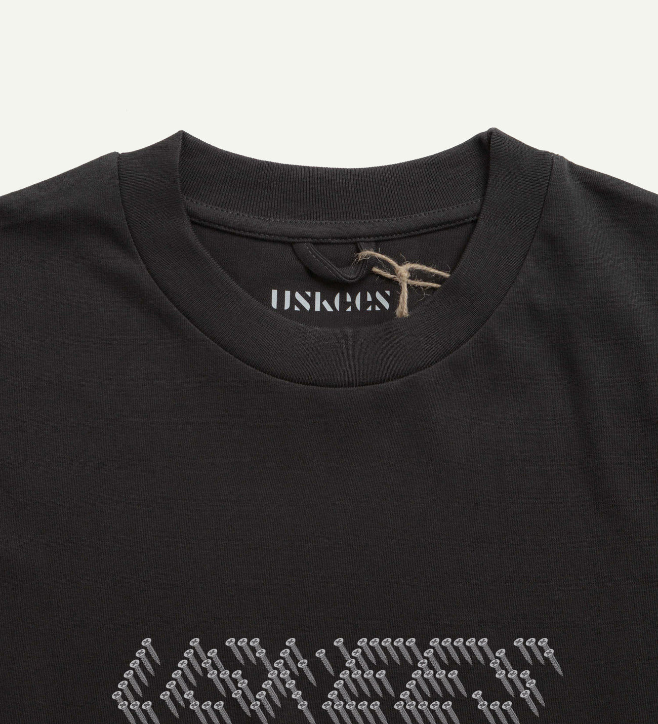 Close-up neckline view of Uskees men's graphic t-shirt in black showing the philips head screw graphic and the texture of the enzyme washed, organic cotton jersey material.