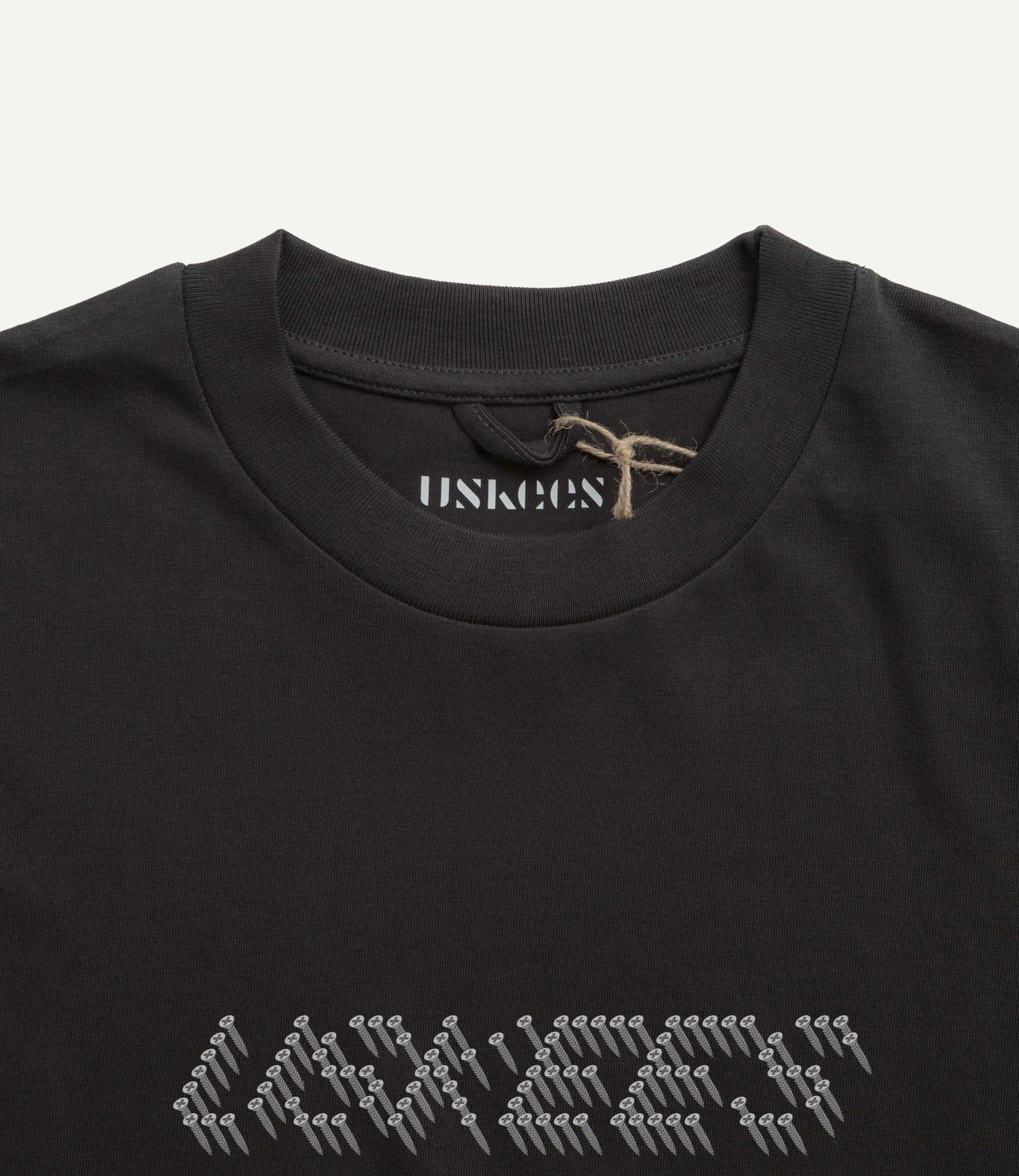 Close-up neckline view of Uskees men's graphic t-shirt in black showing the philips head screw graphic and the texture of the enzyme washed, organic cotton jersey material.