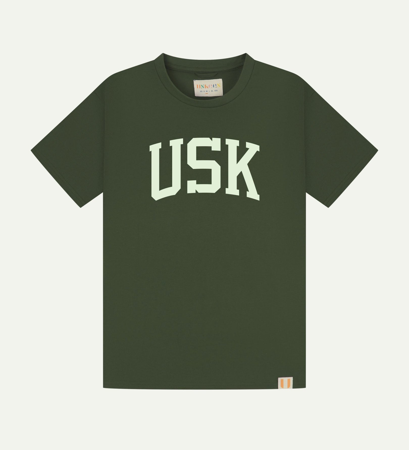 Full flat view of coriander-green organic cotton signature T-shirt for men, showing the varsity inspired 'USK' logo on the chest and the Uskees branding labels on the neck and hem.
