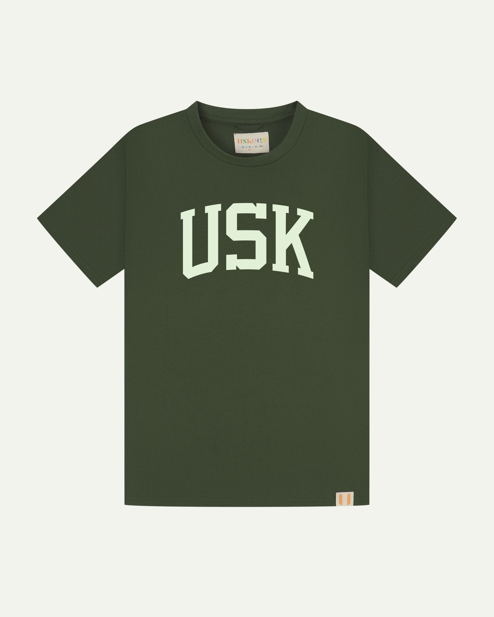 Full flat view of coriander-green organic cotton signature T-shirt for men, showing the varsity inspired 'USK' logo on the chest and the Uskees branding labels on the neck and hem.