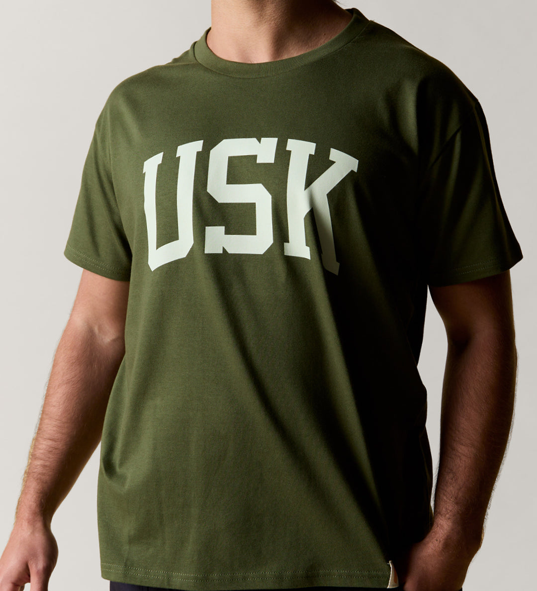 Front view wearing the coriander-green organic cotton signature T-shirt for men, demonstrating the loose, relaxed fit.