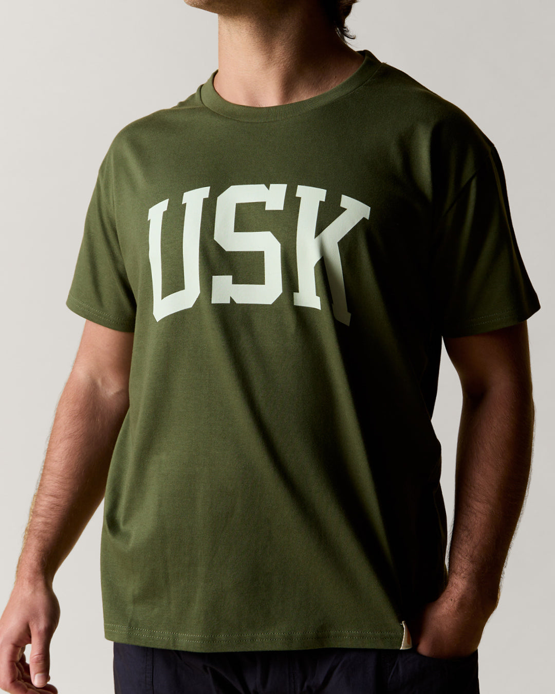 Front view wearing the coriander-green organic cotton signature T-shirt for men, demonstrating the loose, relaxed fit.
