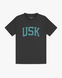 Full flat view of faded black organic cotton signature T-shirt for men, showing the varsity inspired 'USK' logo on the chest and the Uskees branding labels on the neck and hem.