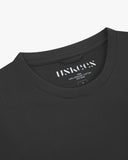 Neckline close-up of Uskees faded black organic cotton T-shirt showing hanging loop and branding label.