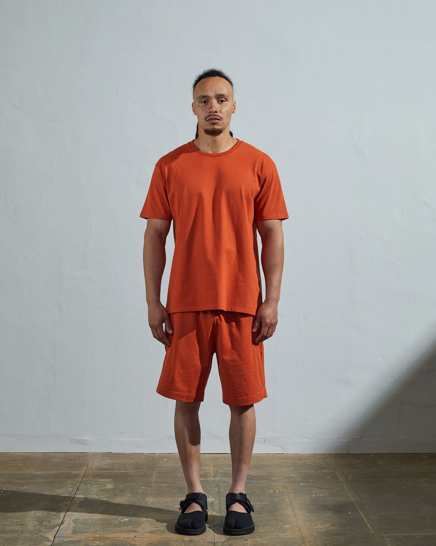 Full-length front view of model wearing golden-orange organic cotton #7006 jersey T-shirt by Uskees paired with matching #7007 shorts.