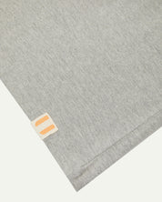 Hem close-up of the grey marl organic cotton T-shirt showing texture of the medium weight organic cotton jersey and the small square Uskees branding tag.