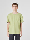 Top-half view of model wearing 7006 green-yellow organic cotton t-shirt, paired with Uskees dark blue pants